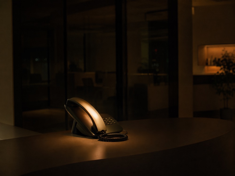 A reception phone glowing softly at night in a dark, closed office